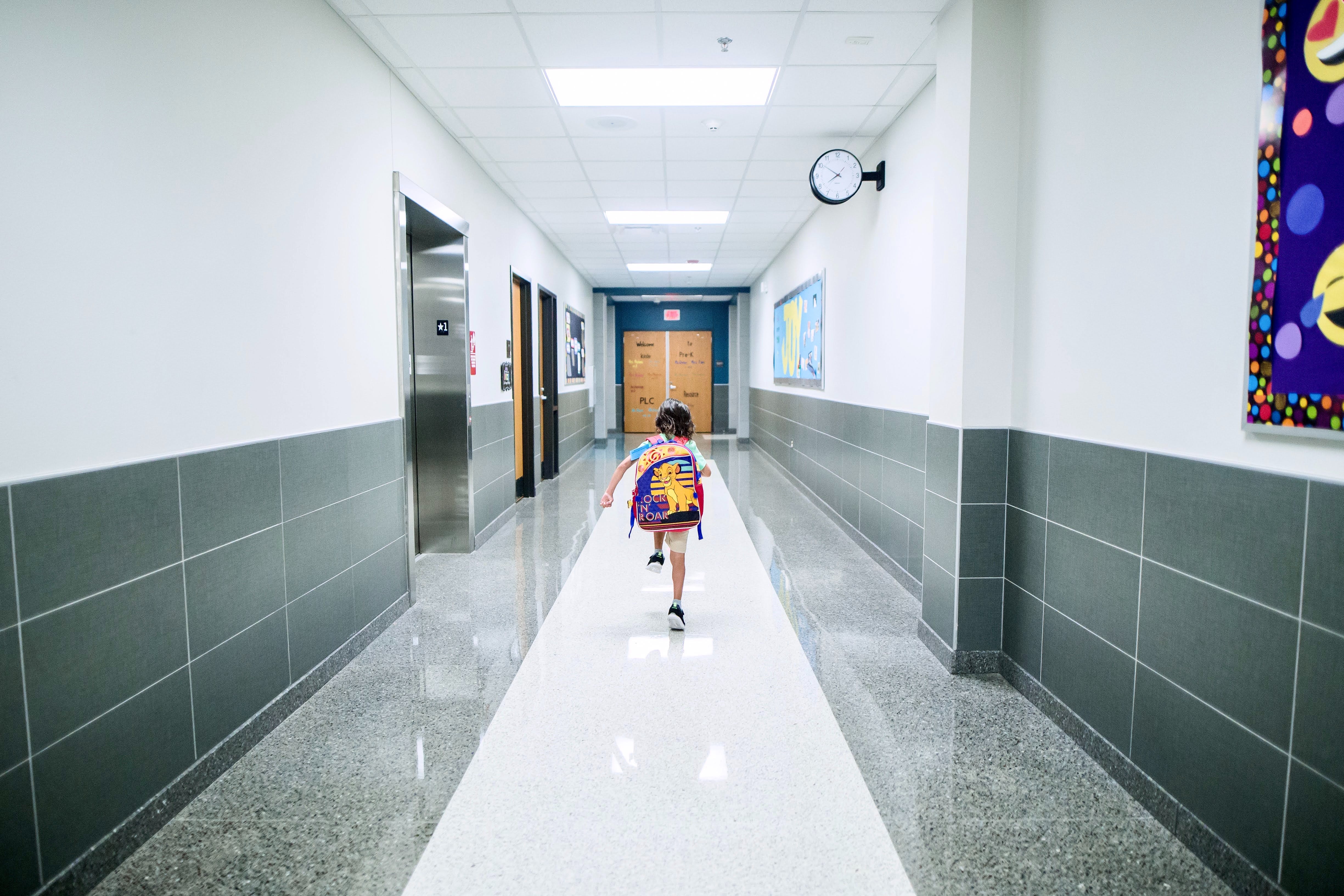 Photo showing a boy running through the hallway of a school.