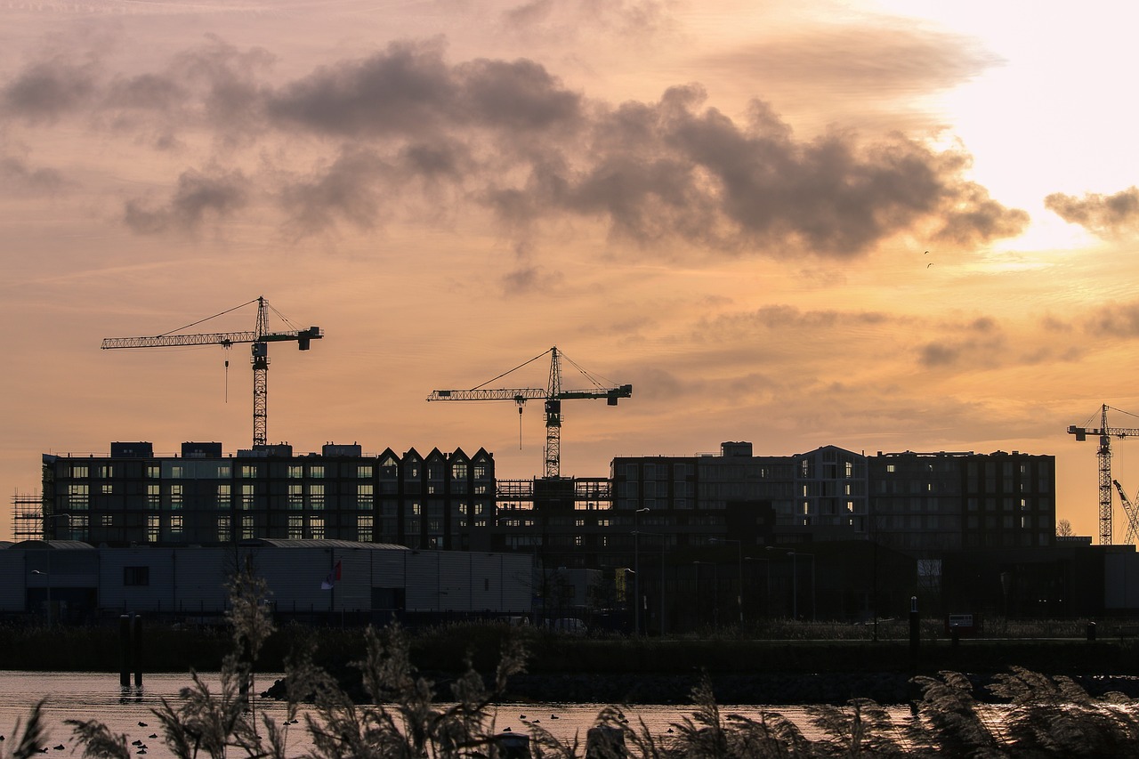 Construction of apartments silhouetted against a sunset.
