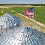 Aerial shot of grain silos on American farmland in North Carolina with a waving US flag.