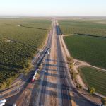 gray asphalt road between green grass field during daytime
