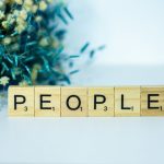 a wooden block spelling people next to a bouquet of flowers
