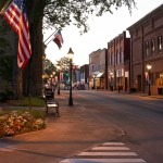 Small town street at dusk with american flags.