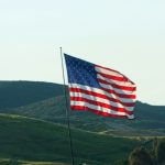 American flag waving on a pole with hills behind