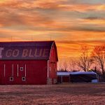 a red barn sitting in the middle of a field