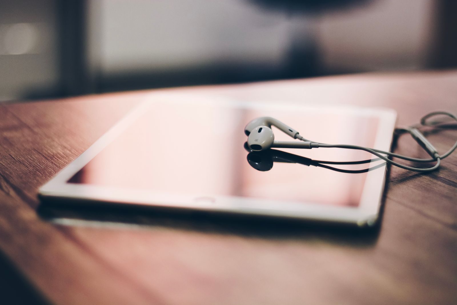 A tablet with earphones rests on a wooden surface, highlighting modern technology and connectivity.