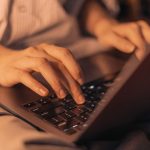 A person's hands typing on a laptop.