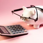 A piggy bank wearing glasses next to a calculator