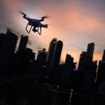 silhouette of quadcopter drone hovering near the city